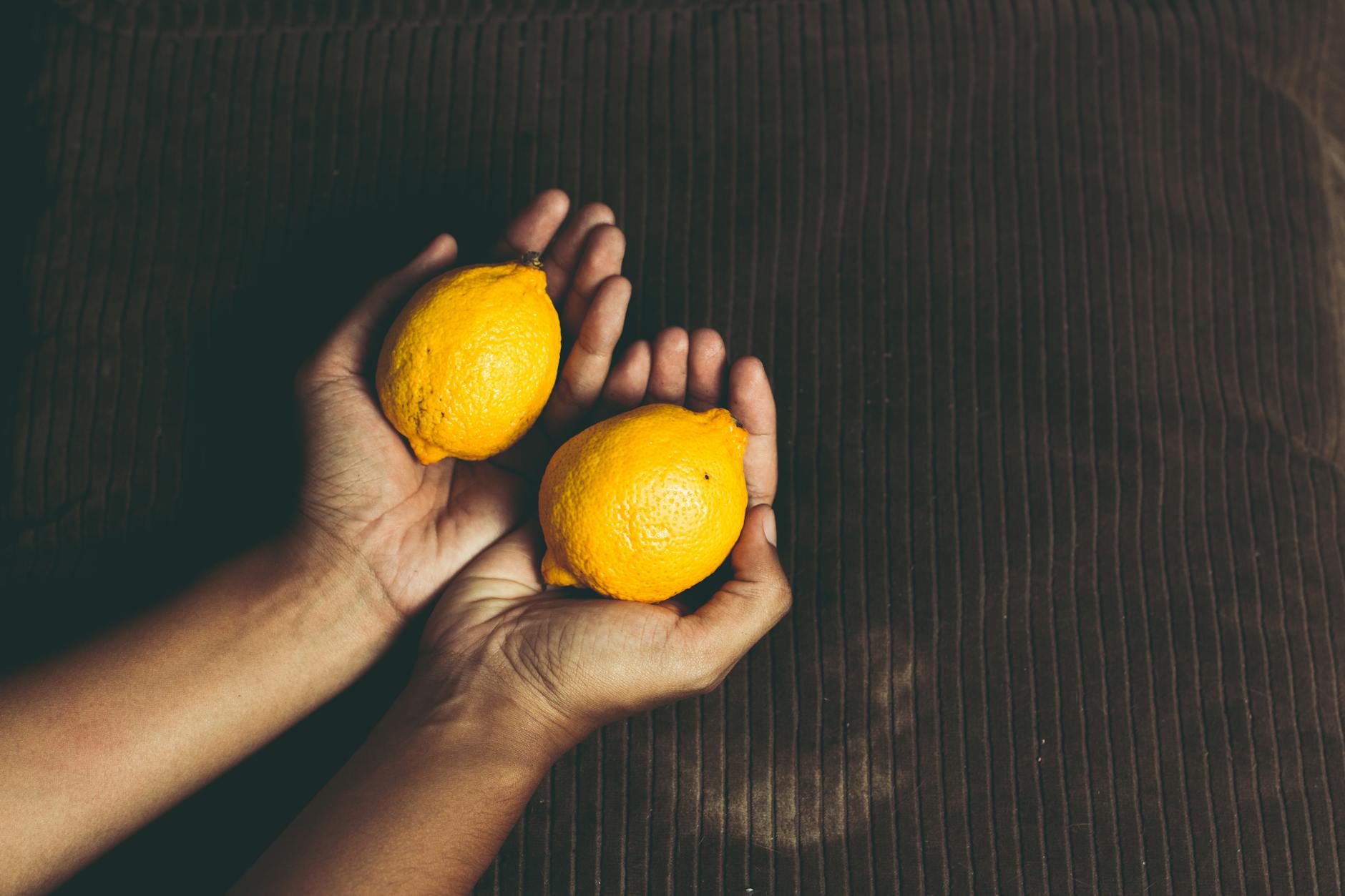 Close-up of hands holding a sleek lemon vibrator against a purple background, symbolizing pleasure restoration