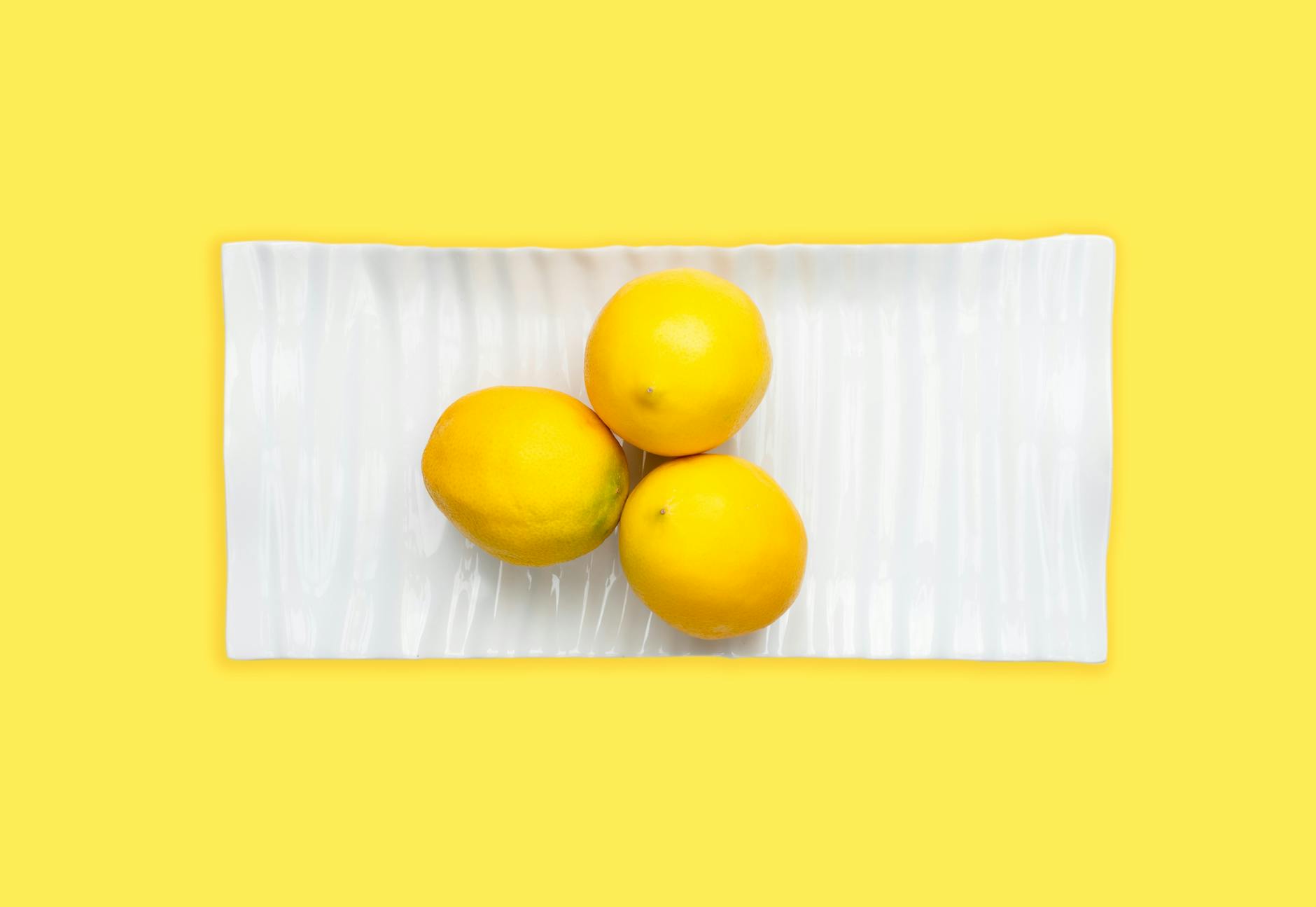 Three fresh lemons arranged on a white surface, symbolizing the natural pleasure of Nancy Lemons vibrators designed for couples