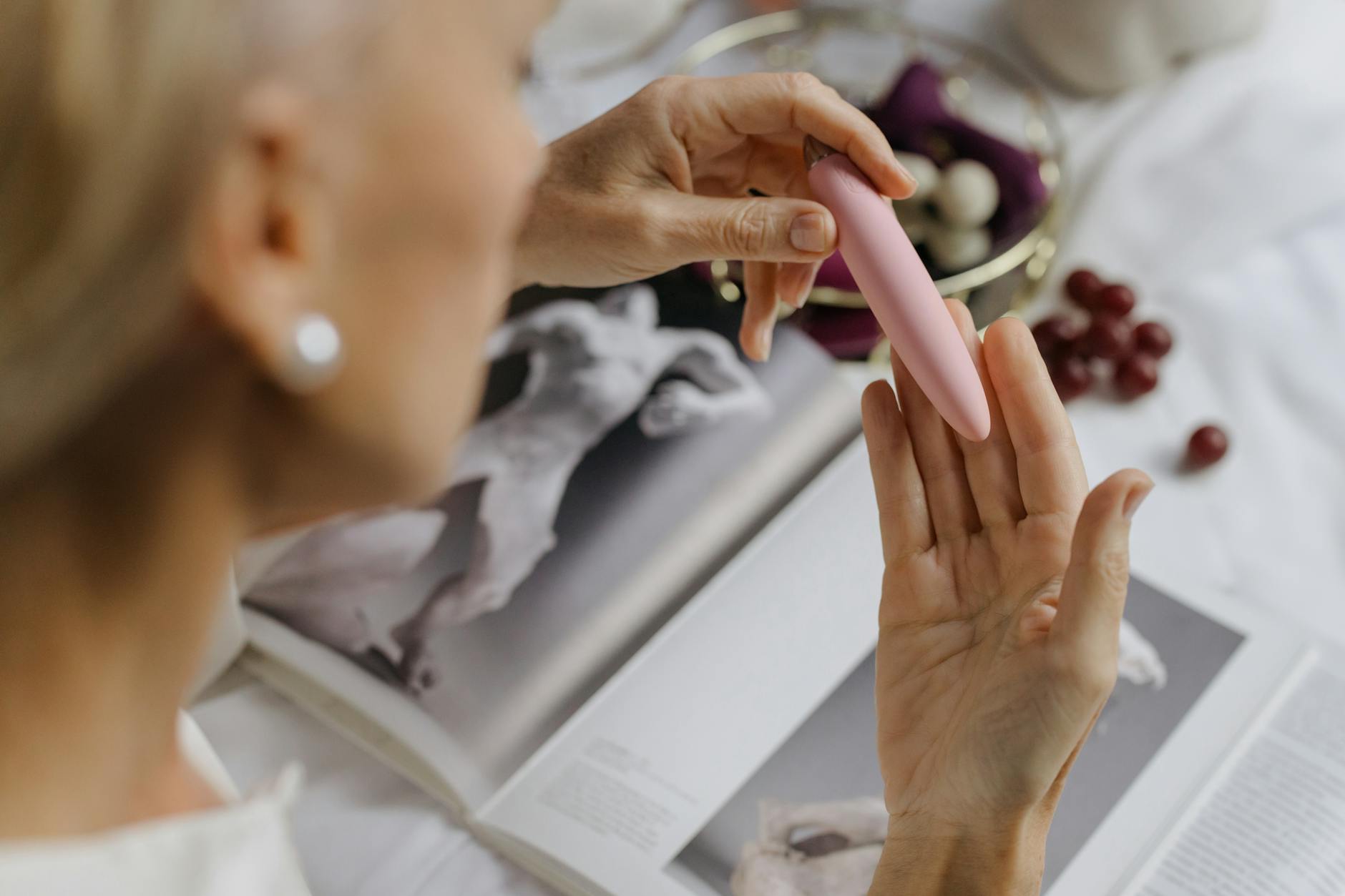 Woman holding blue and pink silicone vibrators with thoughtful expression