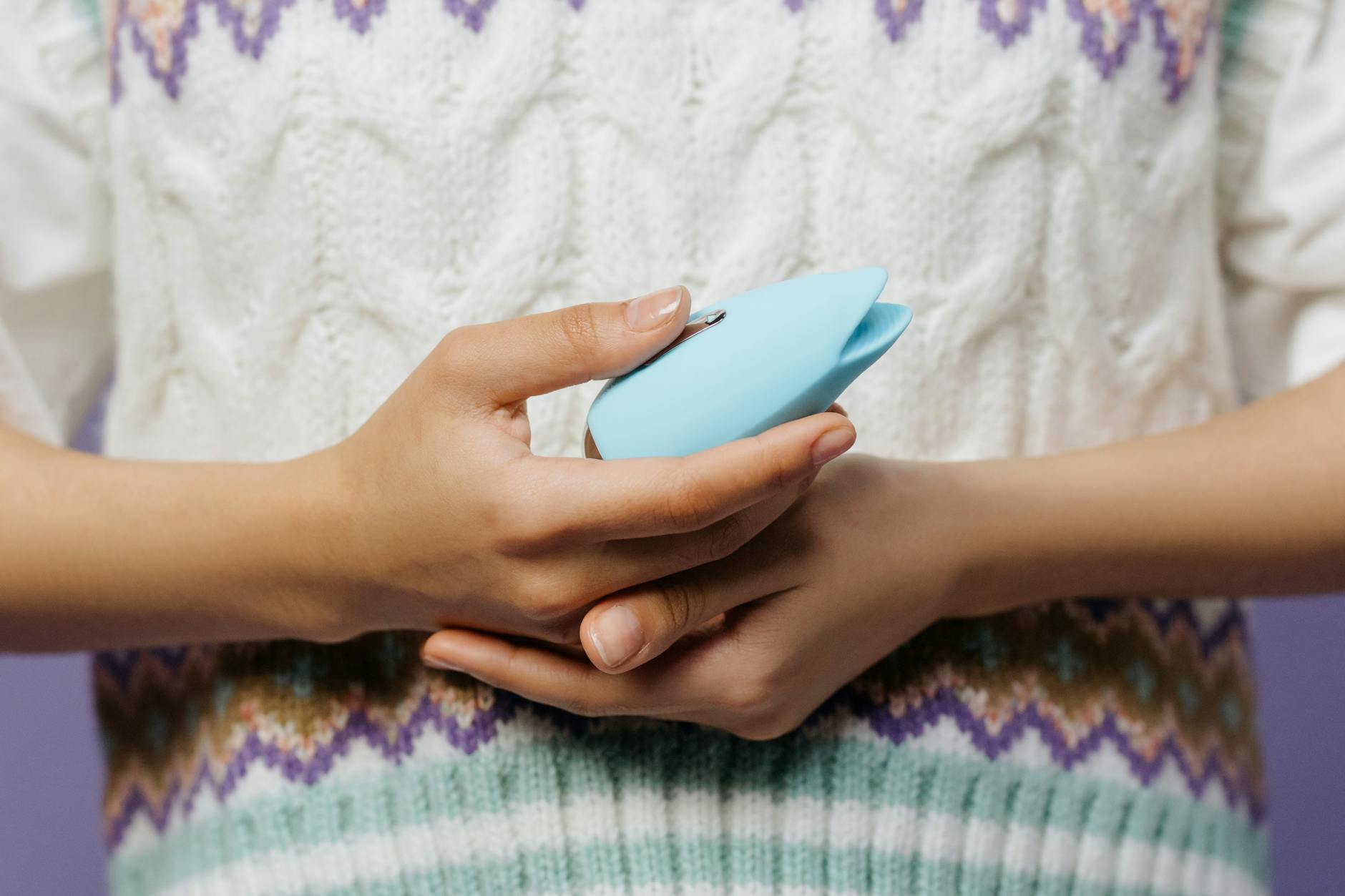 Hands holding a blue silicone vibrator, close-up.