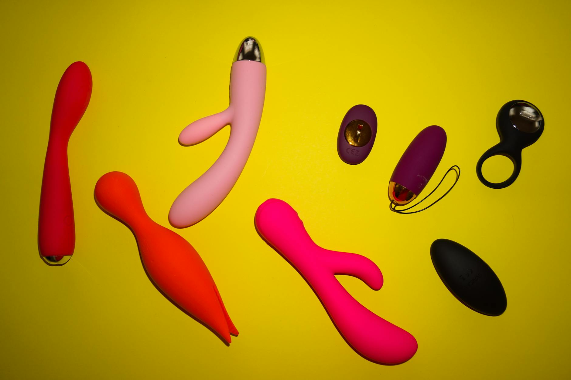 Vibrant collection of various clitoral vibrators displayed on a bright yellow surface