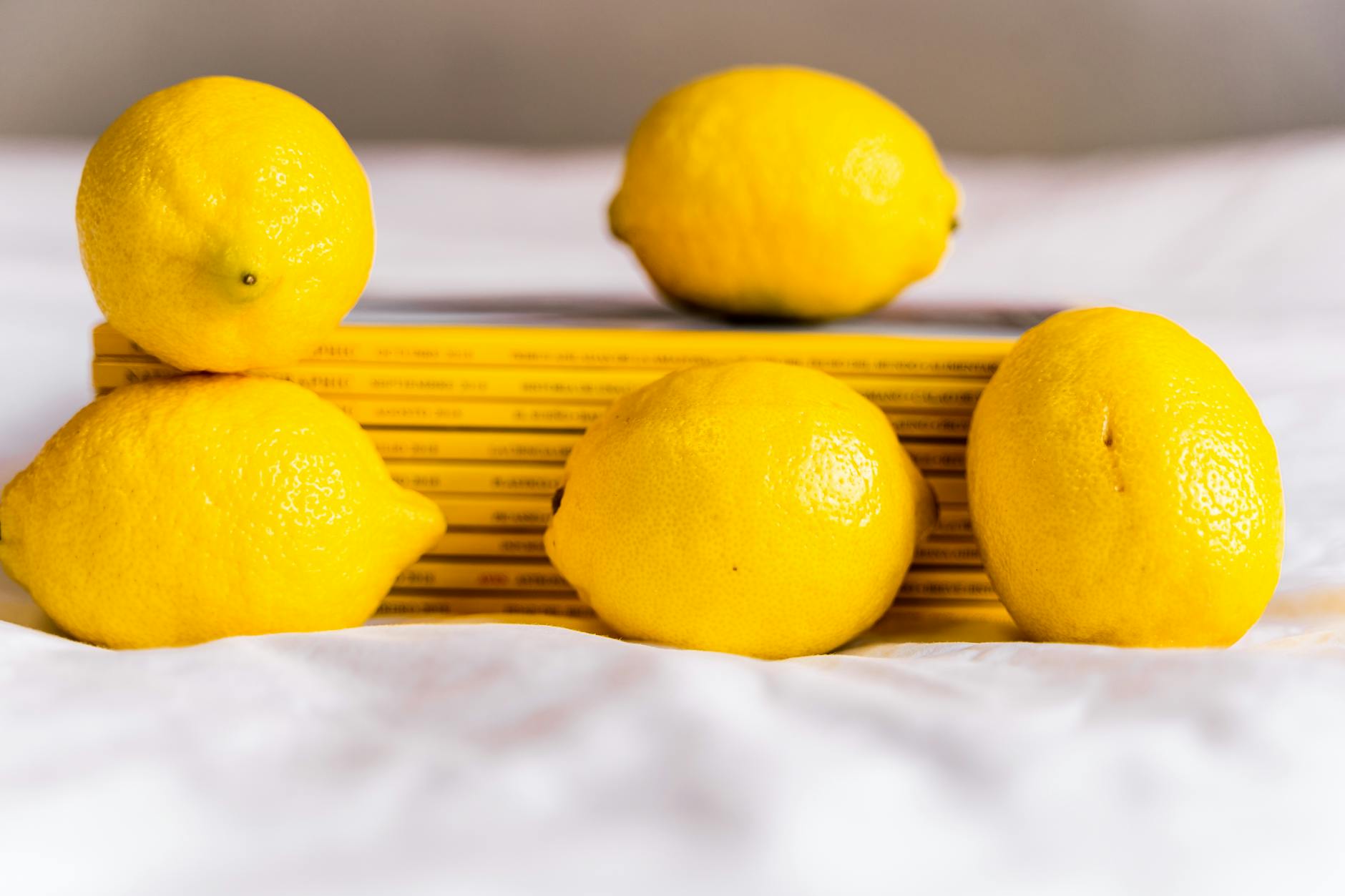 Composition with fresh lemons and stacked books on white surface.